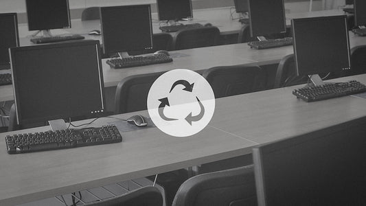 A computer monitor sits in a computer lab on a desk.